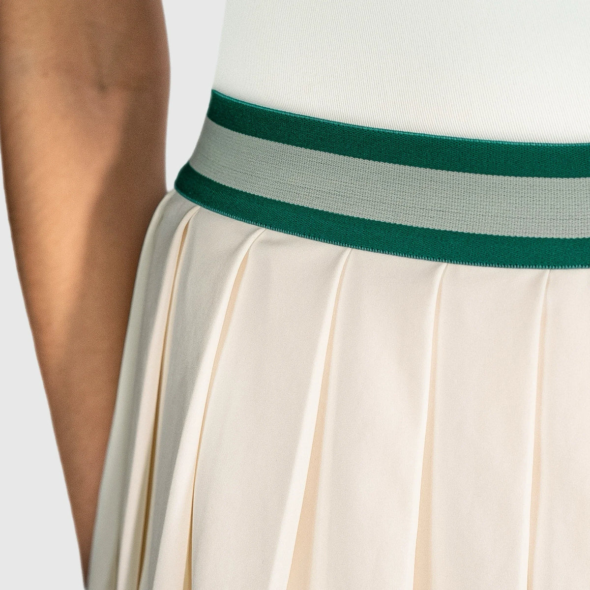 Close-up of a person wearing a QUAD Flare Padel Skirt with a green and gray striped belt on a light background