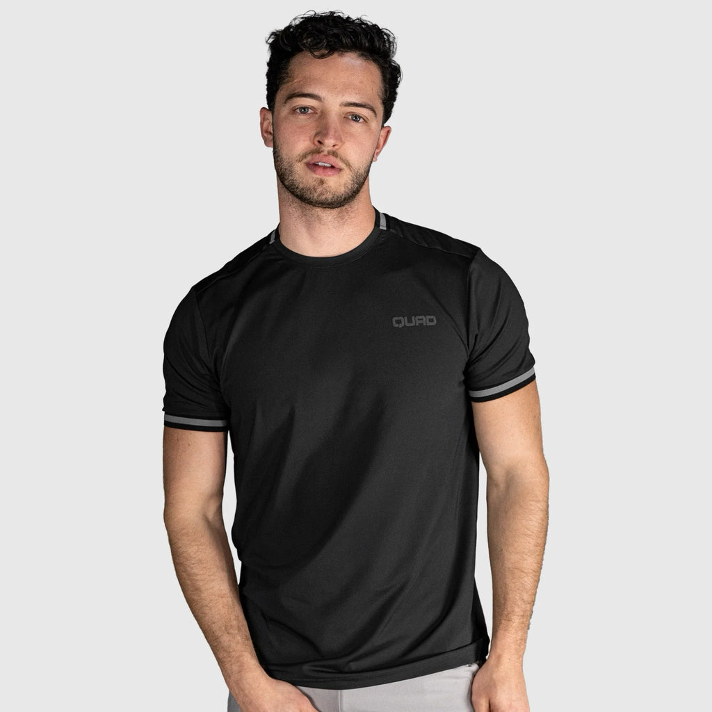 Man wearing a black athletic shirt with a brand logo on a light gray background
