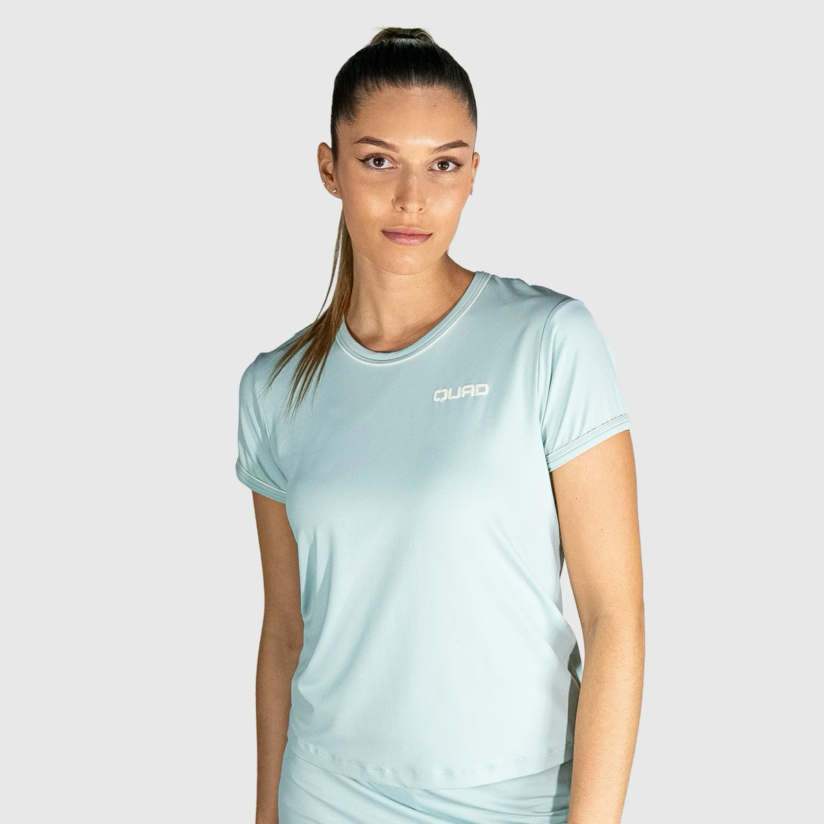 Woman wearing a New Regular Padel shirt with a brand logo on a grey background