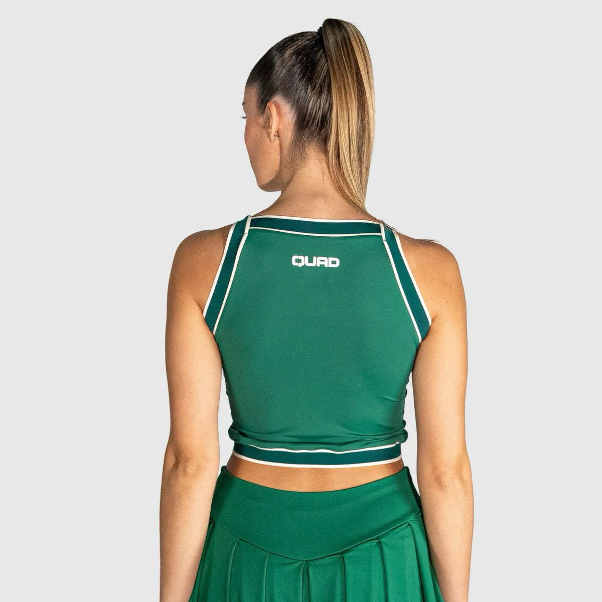 Person wearing a slice padel top with 'QUAD' branding on a light grey background