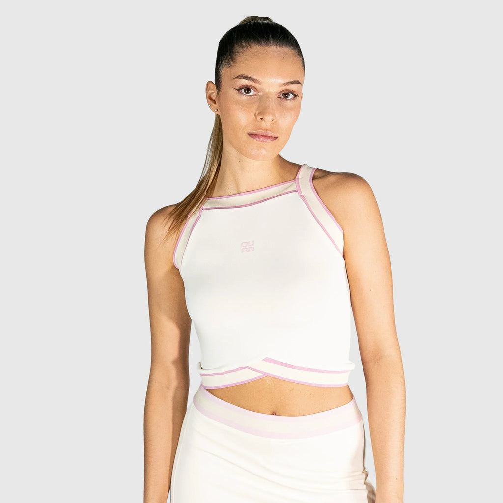 Woman wearing a white slice padel top with pink accents on a light grey background