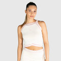 Woman wearing a white slice padel top with pink accents on a light grey background